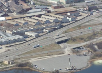 A lake cleanup support area near I-690 with crane that will lift equipment into the water.