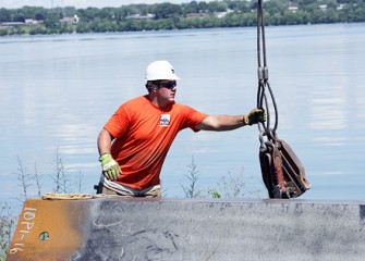 Worker Attaches Vibratory Hammer to Panel