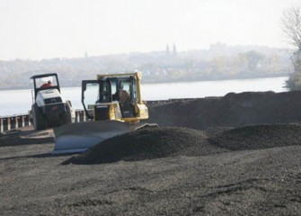 Workers move gravel behind the barrier wall.