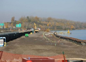 Barrier wall steel panels are driven into the ground to stop groundwater from reaching the lake.