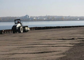 Worker compacts the shoreline along Phase II of the Barrier Wall.