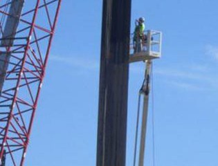 Workers check the steel before it is driven into the ground.