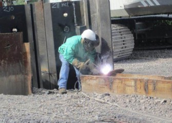 A worker uses a torch during barrier wall construction.