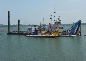 Largest dredge during final testing phase with support boat in the foreground.