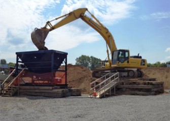 An excavator feeds sand into a hopper.