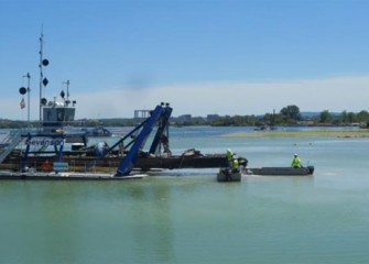 Workers perform routine maintenance on the dredge cutter head to keep it free from pieces of debris.