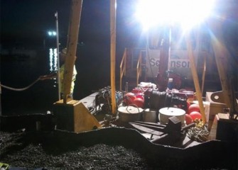 A crew prepares for night maintenance work on a support barge.