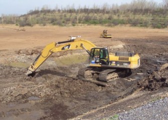 Worker uses an excavator to move clean soil to build the new wetlands