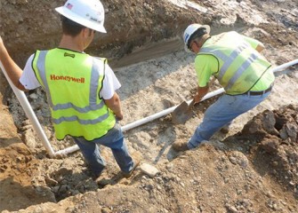 Workers install a monitoring pipe for taking water samples