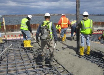 Workers pour concrete for concrete pad.