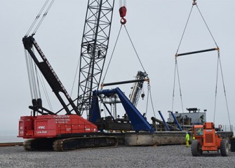 Cranes prepare to lift a dredge into the lake.
