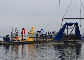 A support barge pushes the dredge into place to continue assembly.