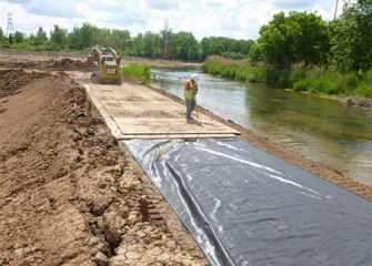 Workers prepare the banks for heavy equipment to access the creek.