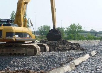 Excavators place dried material into trucks that transport the material to a separate landfill for final storage.