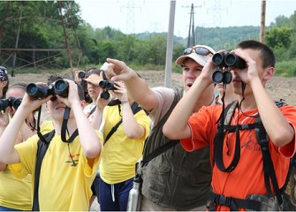 Experts from Montezuma Audubon Center and Onondaga Audubon Society lead students on a birding walk to track native species at the Geddes Brook wetlands