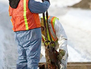 Worker Attaches Cable to Wall Section