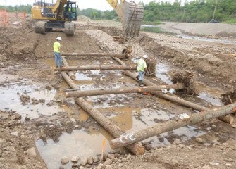 Logs are guided into place to form a "crib wall" that will help stabilize the creek channel and provide habitat.