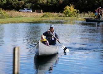 Neil Anderson, of Auburn, New York, paddles as Connor Ryan, also of Auburn, enjoys a canoe ride at the 2012 Honeywell Sportsmen’s Days.