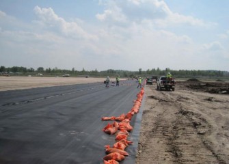 Liner Forms the Second Impermeable Layer, Installed Above the Clay Layer. Orange Sand Bags Temporarily Hold the Liner in Place