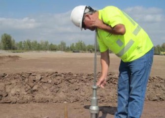 A Quality Control Technician Uses a Core Sampler to Test the Clay Layer for Permeability
