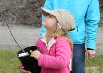 A young Corps volunteer admires the young tree she is about to plant.