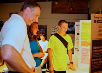 Honeywell Syracuse Program Director John McAuliffe (left) joins parents in viewing student posters before the recognition event.