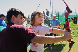 Eagle Scout Andreu Nutter, of Cicero, N.Y., teaches Darby Ryan, of Sennett, N.Y., how to shoot an arrow at the <em>2013 Honeywell Sportsmen's Days at Carpenter's Brook</em>.