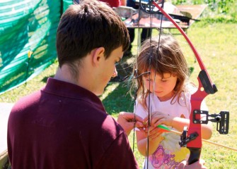 Darby Ryan, of Sennet, learns how to attach an arrow to the bowstring from Eagle Scout Andreu Nutter of Cicero.