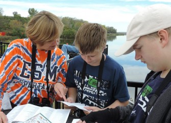 Seventh-grade science teacher and Honeywell Institute for Ecosystems Education alumna Sue Verbeck works with Colin Hensinger (center) and Logan Rowe to identify bird species.