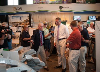 SUNY ESF President Dr. Murphy (center-left) shows Lt. Gov. Duffy (center-right) a dredge cutter head at Honeywell’s lake cleanup display.