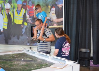 Kevin, Amber, and Eli Geidel of Liverpool, New York, view the Onondaga Lake watershed map at Honeywell’s exhibit.