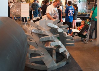 A fairgoer examines the dredge cutter head metal teeth, which help break up lake bottom material before it is suctioned into the dredge and pipeline.