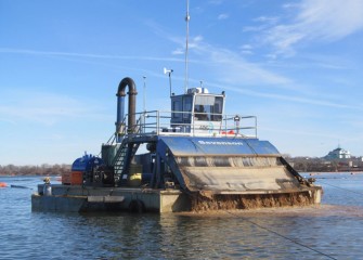 A specialized barge applies cap material consisting primarily of sand to the lake bottom.