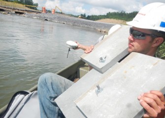 Pennsylvania bluestone slabs, arranged specifically for Nine Mile Creek conditions, are positioned using a handheld GPS device for placement on the creek bottom.