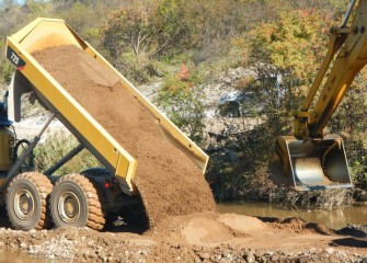 Sand is delivered and placed in Nine Mile Creek with an excavator to create a new creek bottom.