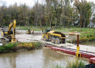 A temporary floating bridge is built across Nine Mile Creek to allow work crews to access a forested wetland.