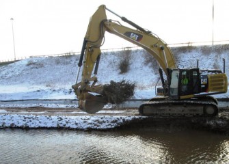 A worker places a log with roots for fish habitat.