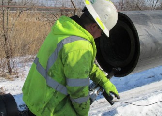 A worker welds spacer rings between the 16-inch and 22-inch pipes.