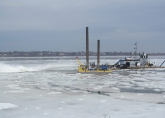 In late March, the largest dredge is pushed out into the lake to help clear ice in the work area.