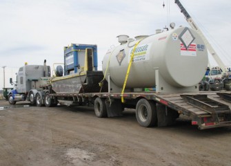 A boat to assist in lake operations and a tank to store biodiesel fuel arrive on a flatbed trailer.