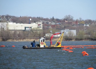 A crew on the tender boat adjusts the silt curtain.