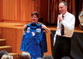 Linda Trippany is presented her flight suit by Honeywell Syracuse Program Director John McAuliffe. Trippany will use the suit at Honeywell Educators @ Space Academy during simulated astronaut training.