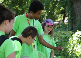 Marcel Young-Scaggs points out identifying characteristics of a plant.  Rebecca Rolnick (right), a 2011 participant in Honeywell Summer Science Week at the MOST and volunteer this year, looks on.