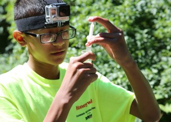 Colin Haven, from Solvay Middle School, measures creek water into a test tube.  Colin is wearing a GoPro camera loaned to students during the week to help record their experiences.