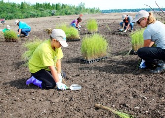 Julie Biondolillo (right) and her daughter Mara, from Pennellville, NY, choose the perfect spot to plant bluejoint grass.