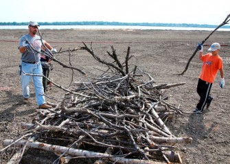 Brayden (right) and his dad Matt Biondolillo build a brush pile near the wetland area.  Brush piles are built in a stable arrangement, with heavier pieces forming the foundation near the bottom, and adequate spacing between branches.