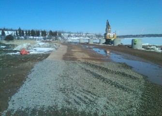 A temporary road of mixed materials is installed along the western shoreline for equipment to travel.