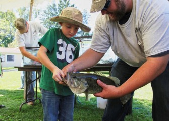 Spencer Weed from Moravia is taught how to grip a largemouth bass on its lower lip.  The fish was caught in Onondaga Lake.