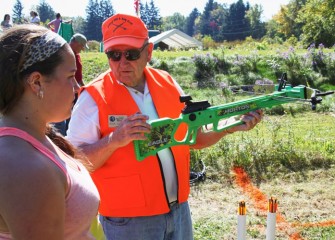 Sportsmen Education Instructor Dick Culkin teaches Kaylee Gadoua from Syracuse how to hold a crossbow.