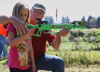 Lance Robson, chairman of the New York State Fish and Wildlife Management Board, shows Keely Gadoua where to position the crossbow on her shoulder.